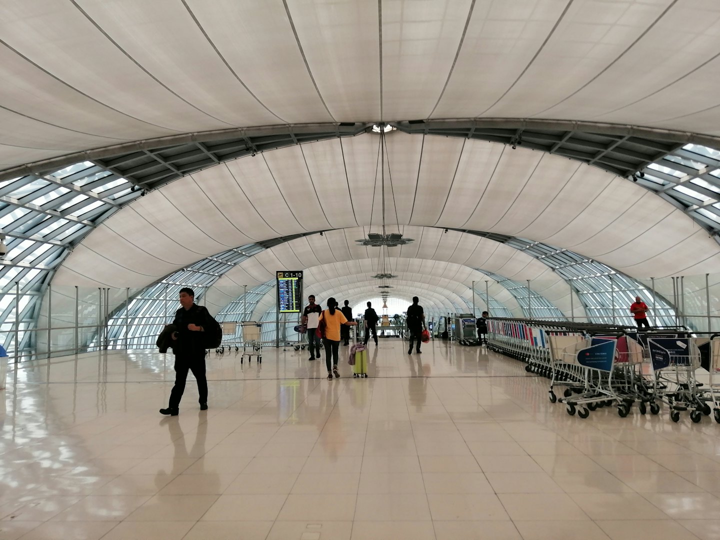 Viaggiatori camminano in un moderno e affollato terminal aeroportuale.