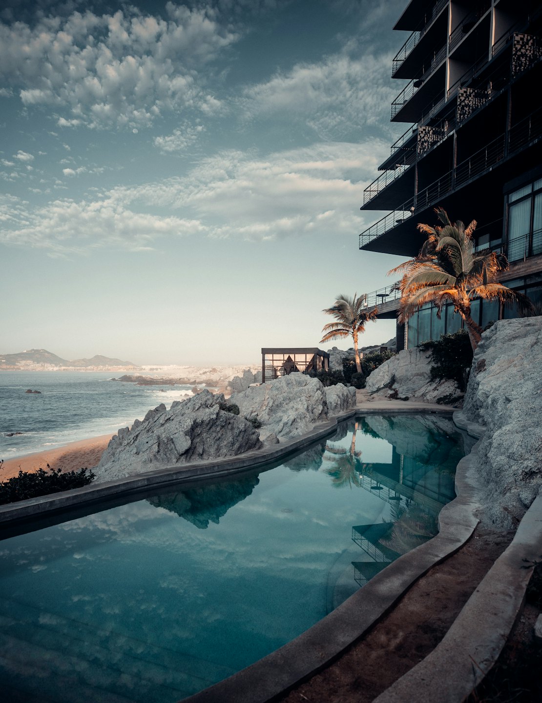 Modern hotel con balconi incastonati in una scogliera costiera rocciosa.