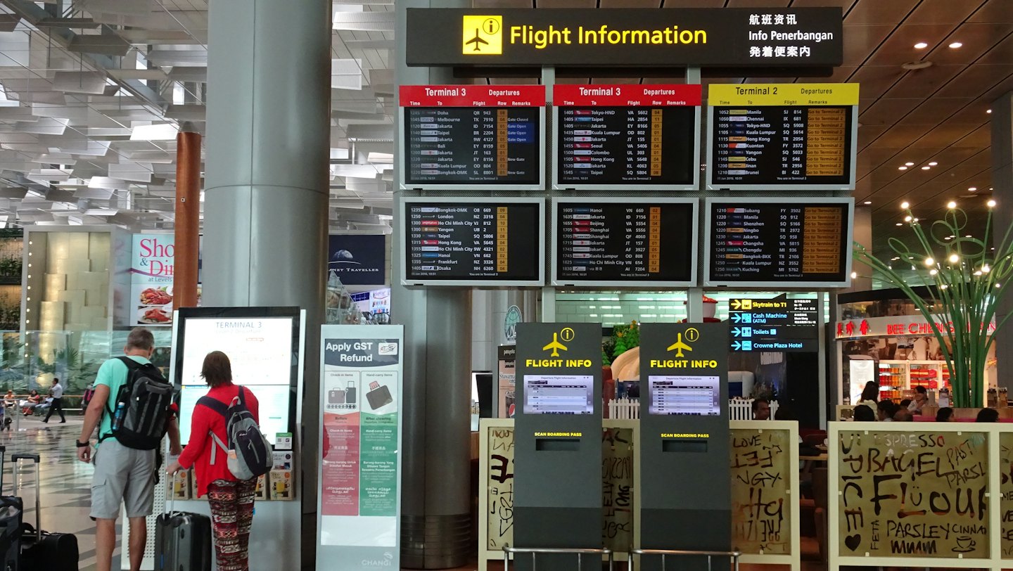 Due viaggiatori controllano le informazioni sui voli a un chiosco digitale dell'aeroporto.